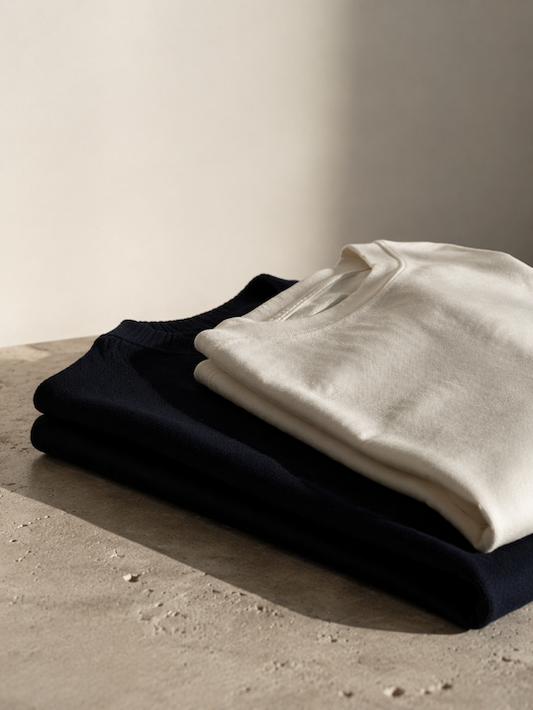 Folded premium clothing in neutral tones, minimalist fashion still life for a modern essentials brand.